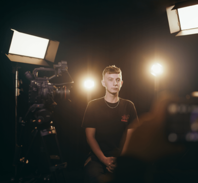 En elev blir intervjuad i en dramatiskt ljussatt fotostudio.