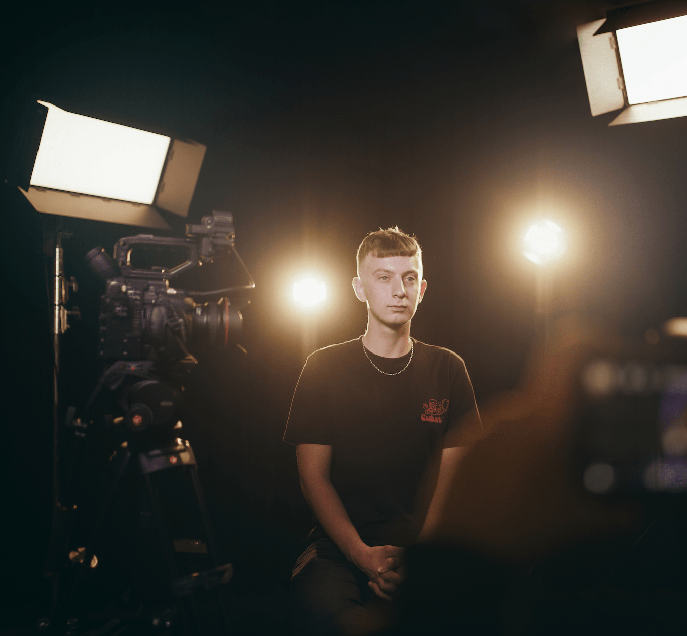 En elev blir intervjuad i en dramatiskt ljussatt fotostudio.