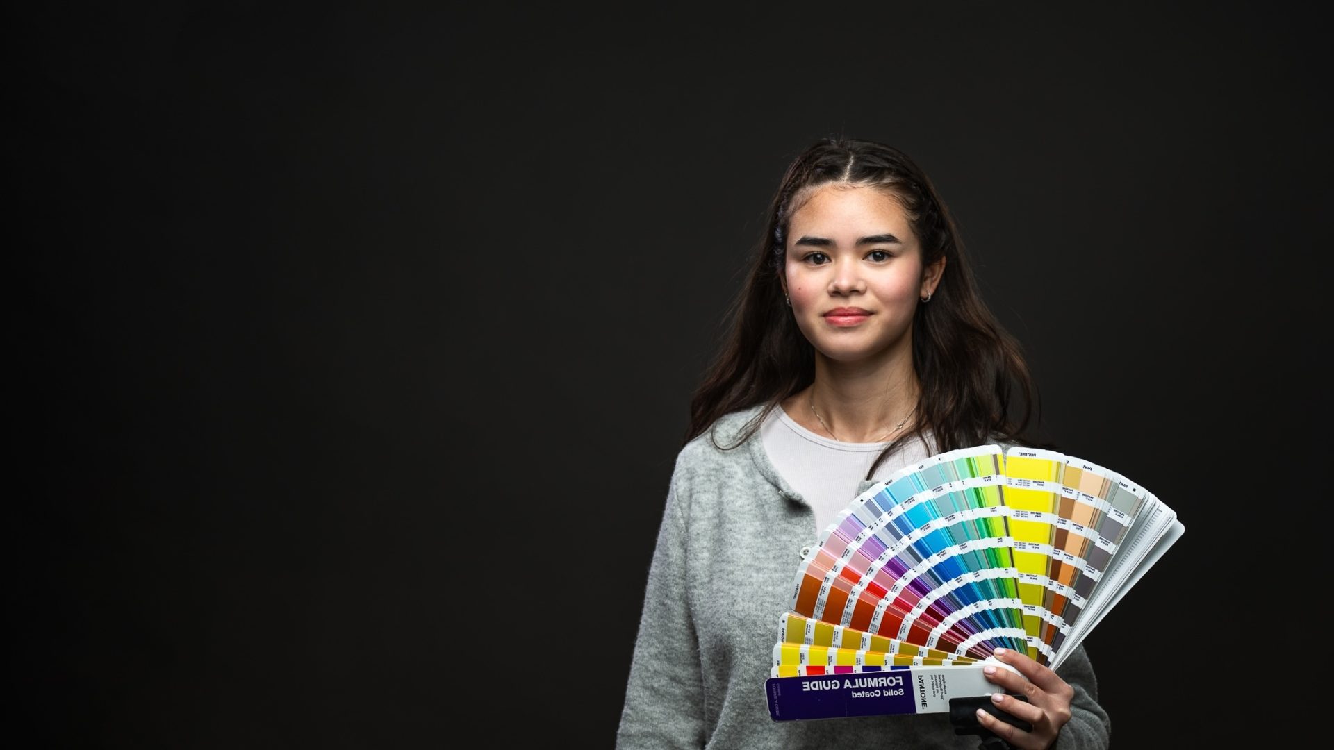 Elev som poserar och håller i en färgkarta